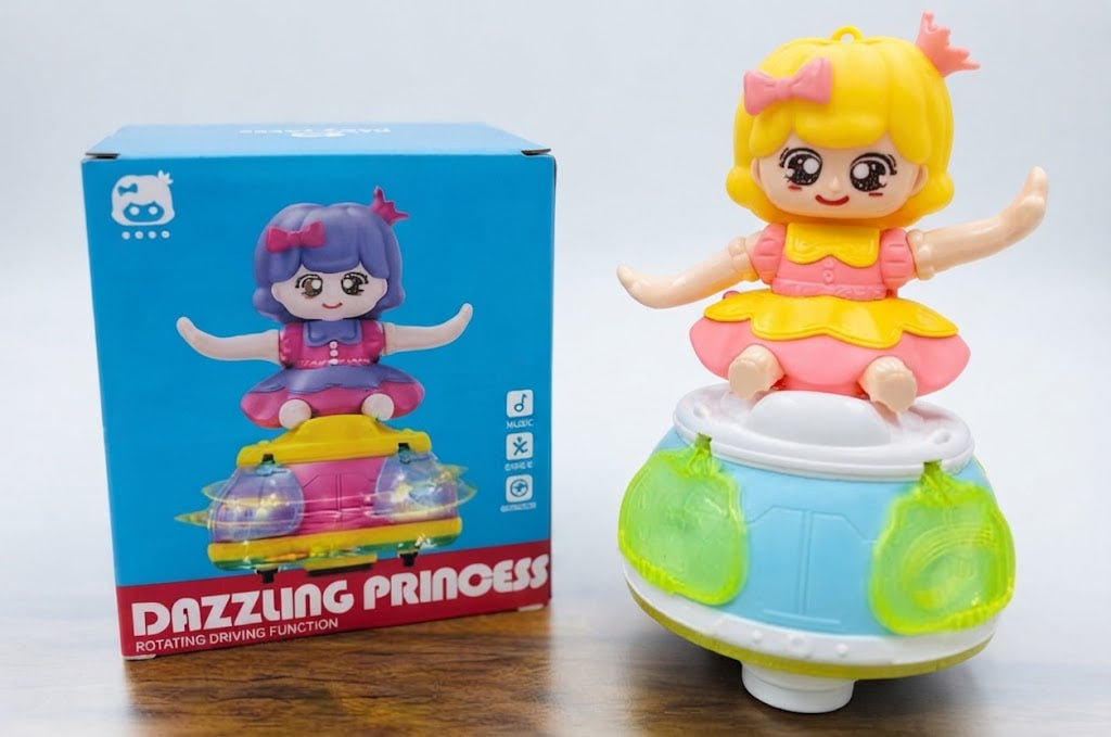 A toy figurine labeled 'Dazzling Princess' shown next to its blue retail box on a wooden surface. The toy features a blonde girl with a pink bow in a pink and yellow dress, sitting on a rotating blue and green base.