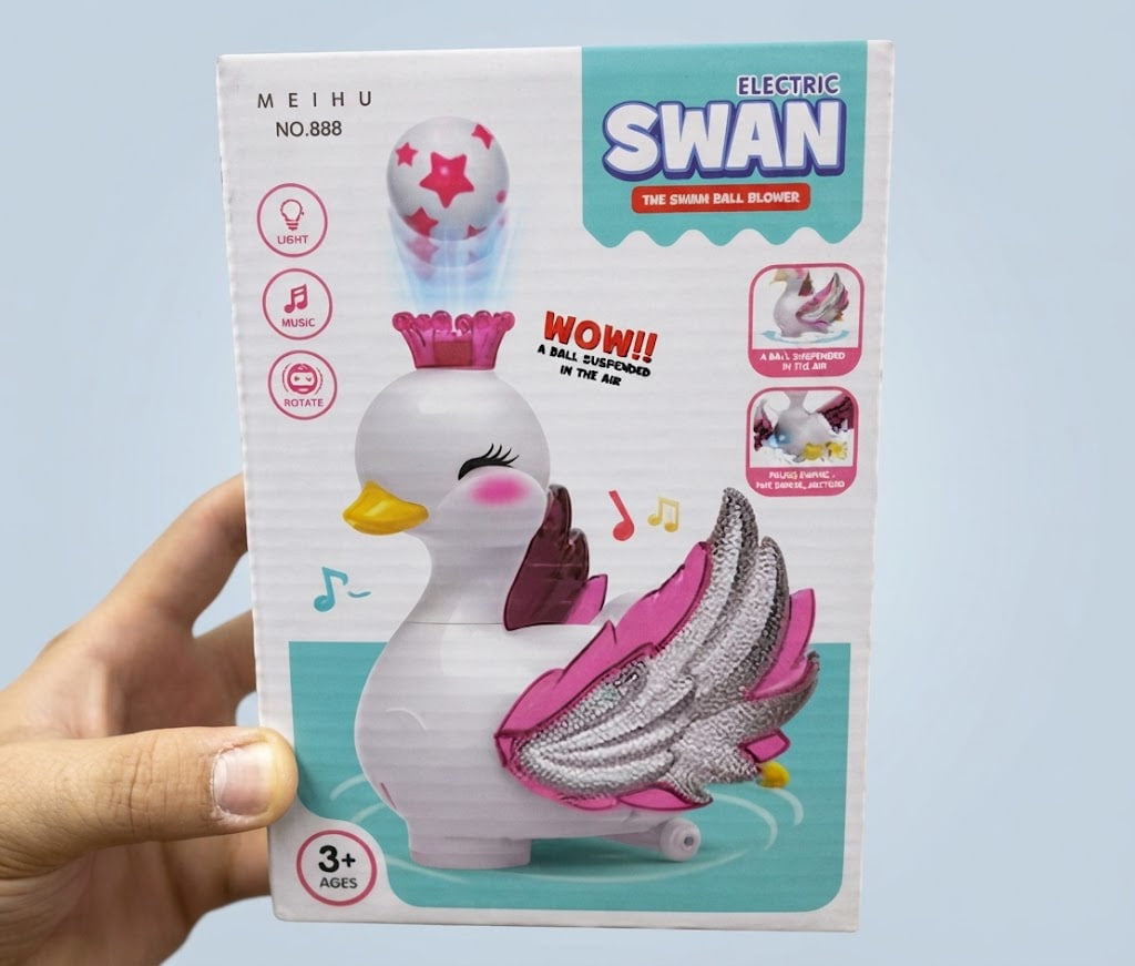 A hand holding a boxed toy product labeled 'MEIHU ELECTRIC SWAN THE CHAIN BALL SLOMER' against a light blue background. The box shows a white swan with pink and silver wings, a yellow beak, and a ball with pink stars, plus feature icons and age 3+ text.