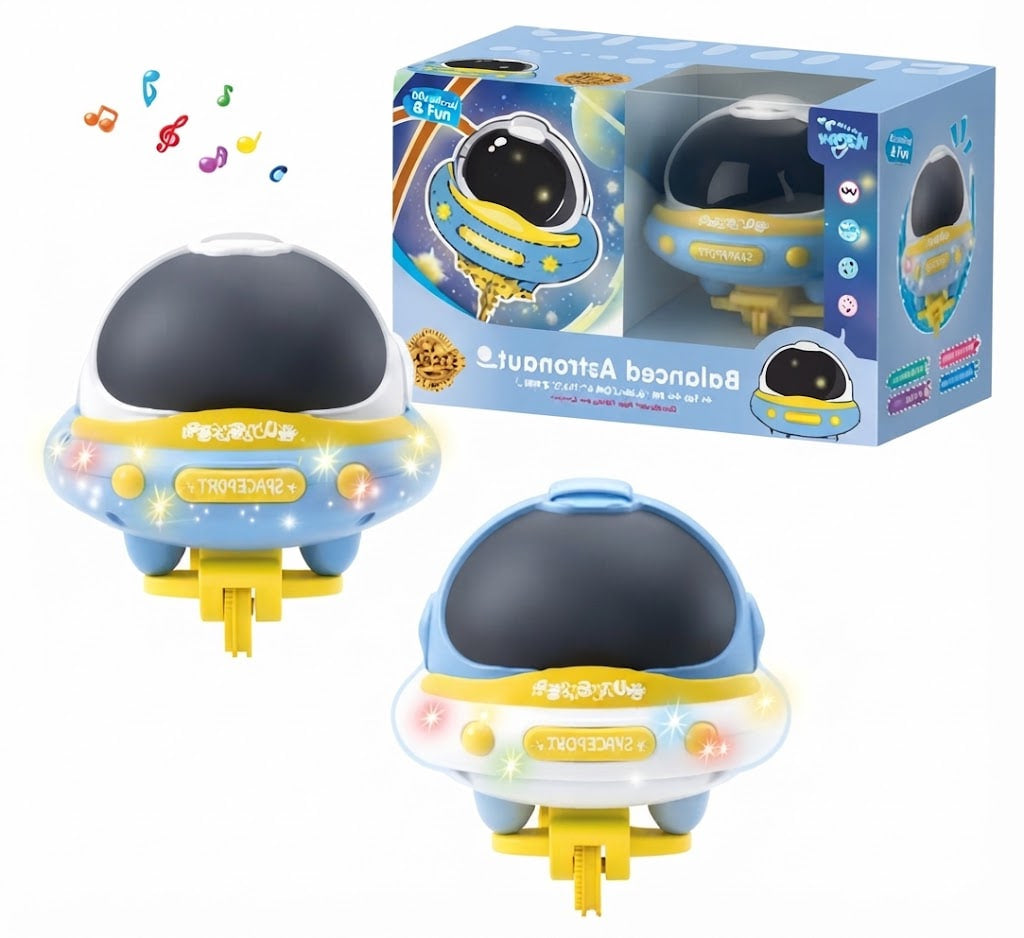 A toy space-themed night light shown with its retail box on a white background. The product is a small astronaut-shaped lamp with a dark dome, blue body, yellow base, and multicolor light accents, plus a blue illustrated package.
