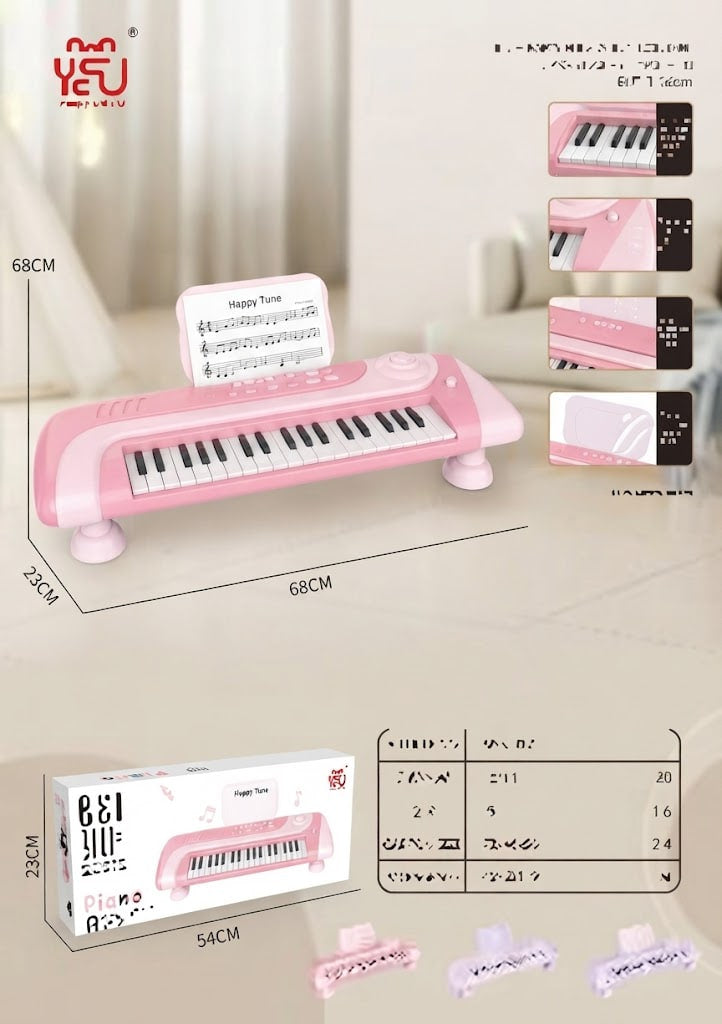 Pink toy electronic keyboard with piano keys, shown with dimension labels, inset detail views, a product box, and a small accessory stand on a light indoor background.