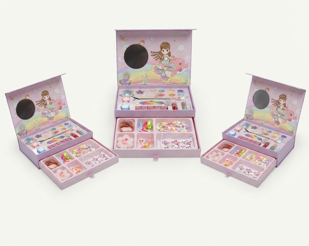 A children's craft or jewelry-making kit displayed in three open pastel pink boxes on a clean white background. The set includes compartments filled with small beads, stickers, tools, and accessories, with illustrated doll artwork on the inside lids and a round mirror visible in each box.
